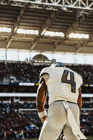 Row of football players in white jerseys shown from behind during a game.