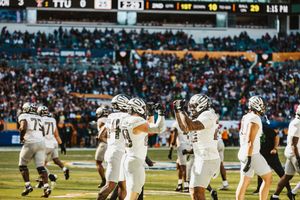 Football players in white uniforms line up in formation during a game.