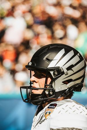 Close-up view of football players wearing silver and black helmets with face masks during a game.