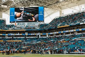 Large video screen and stadium seating visible inside Hard Rock Stadium during sporting event.