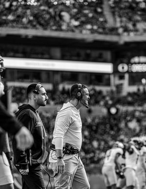 Football players in black and white uniforms interact on the sidelines during a game.