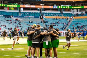 Football team huddled together on the field at Hard Rock Stadium during a game.