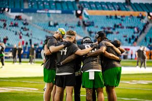 Team huddle formation on the football field with players gathered in a circle.