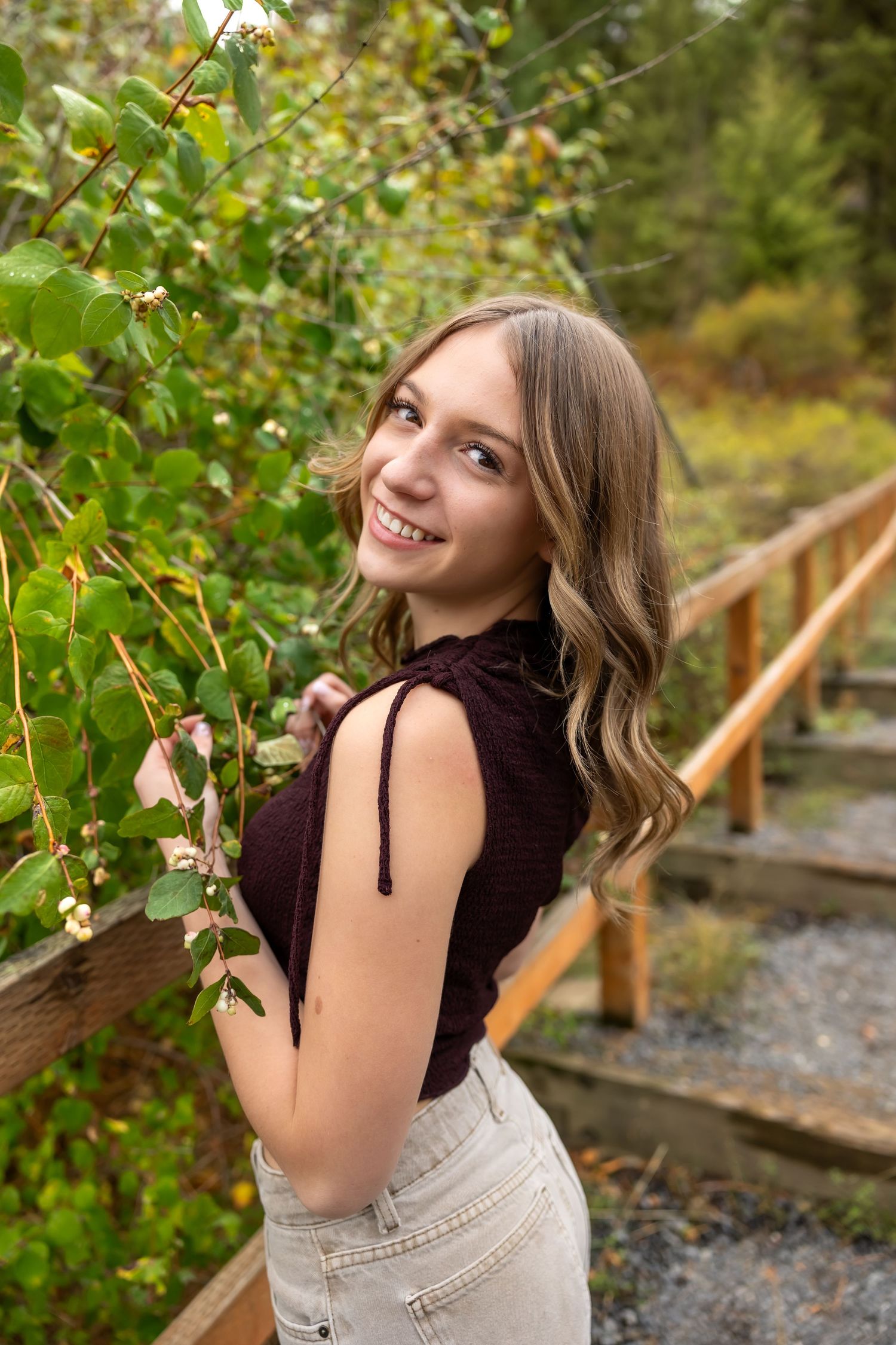 A series of outdoor portraits showing someone in a dark top and light pants posing playfully among green foliage.