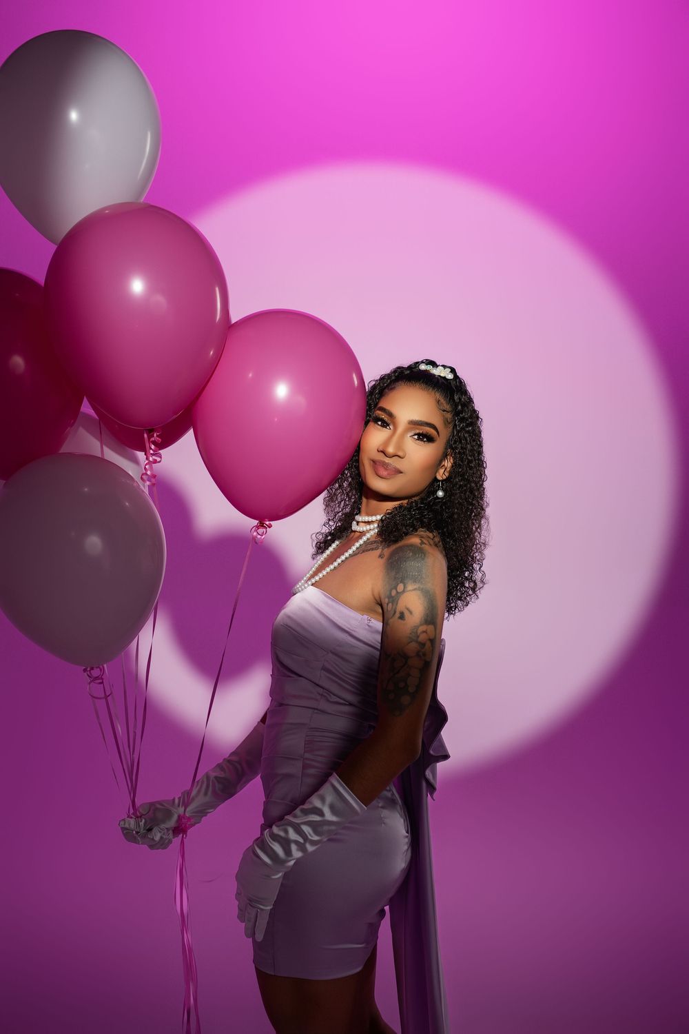 Stylish portrait session with pink and white balloons against magenta background.