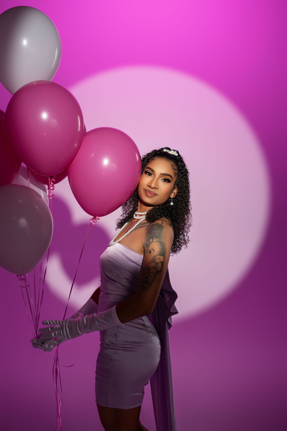 Glamour photoshoot with pink and white balloons against vibrant magenta background.