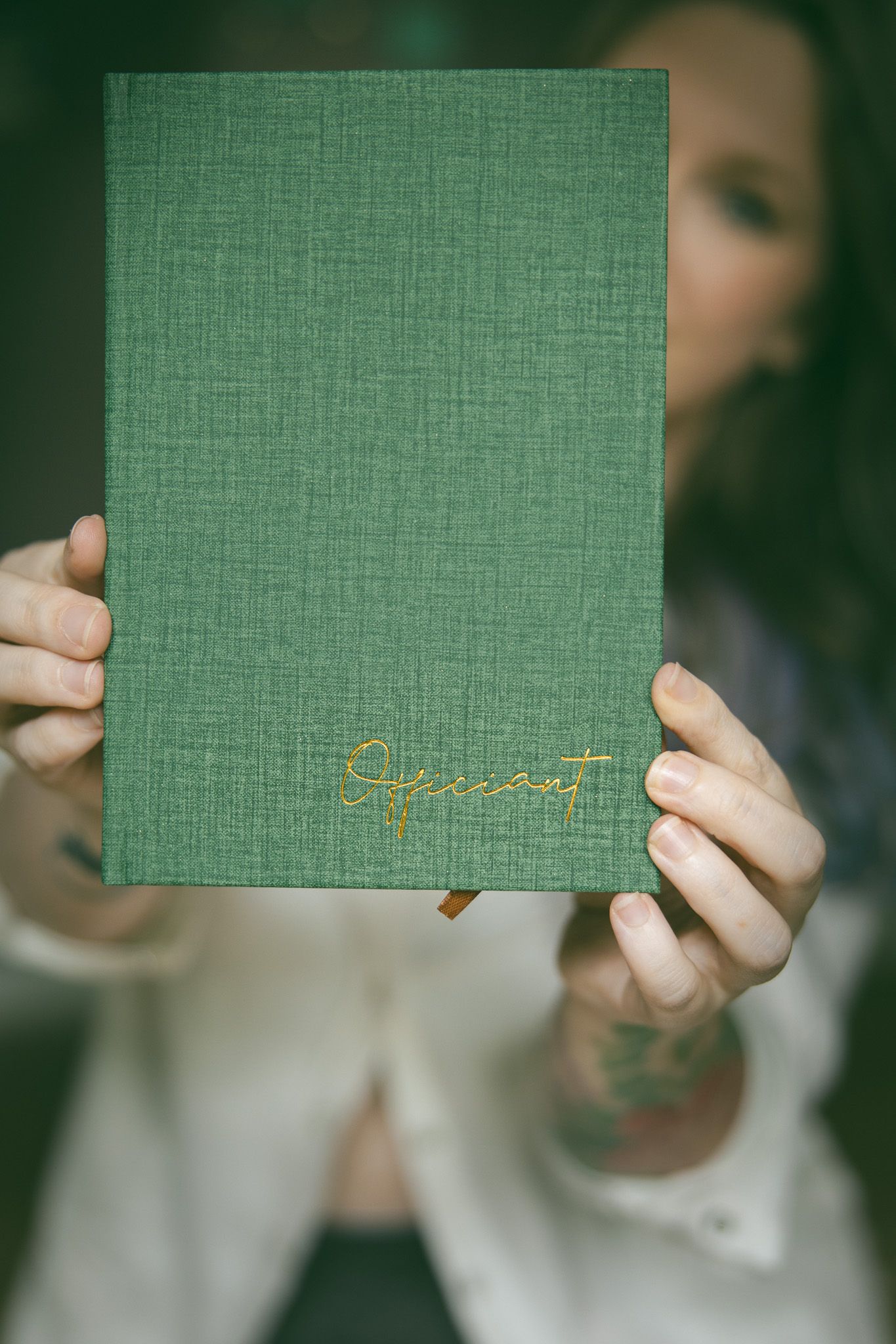 alternative photographer holding officiant book in focus