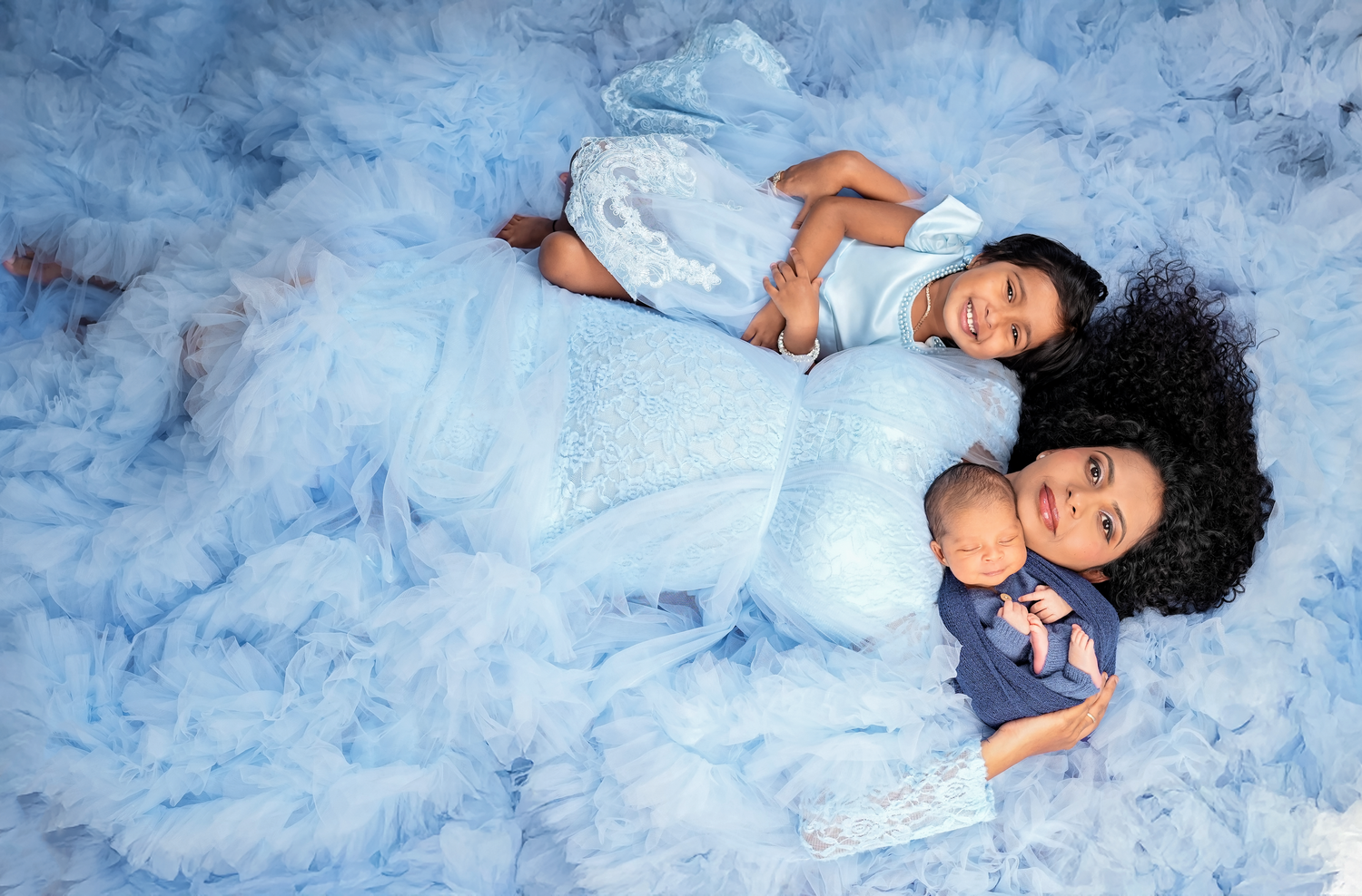 A person in a flowing blue dress lies gracefully on a white backdrop in a series of artistic poses.