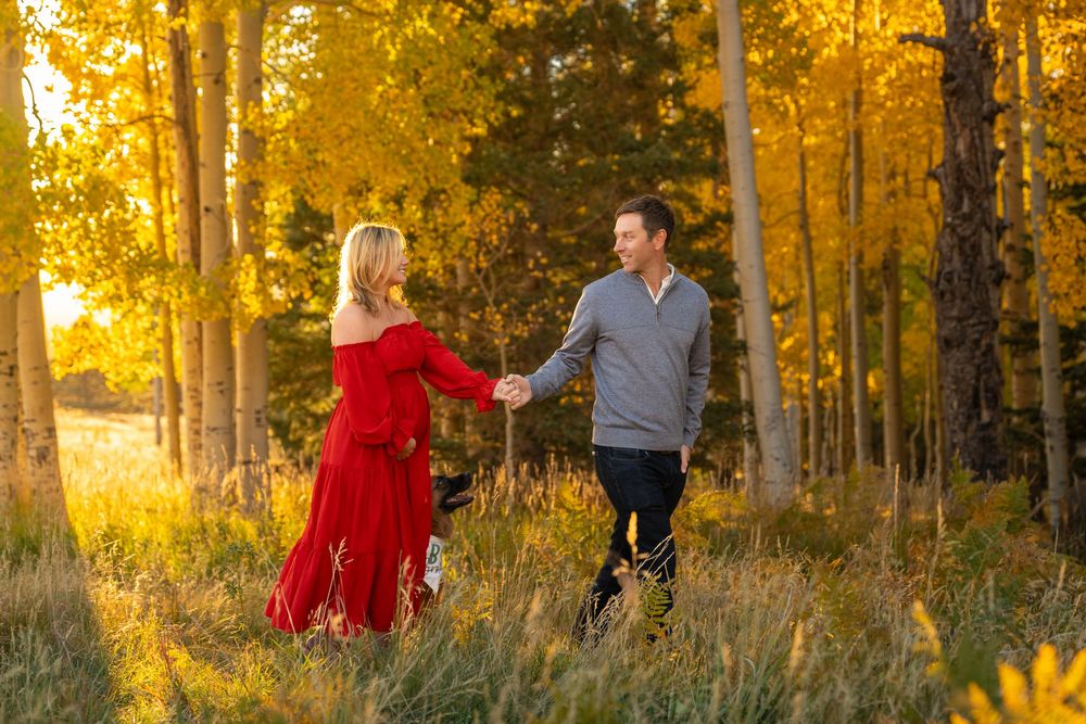 Couple dancing together in a golden aspen forest during autumn sunset.