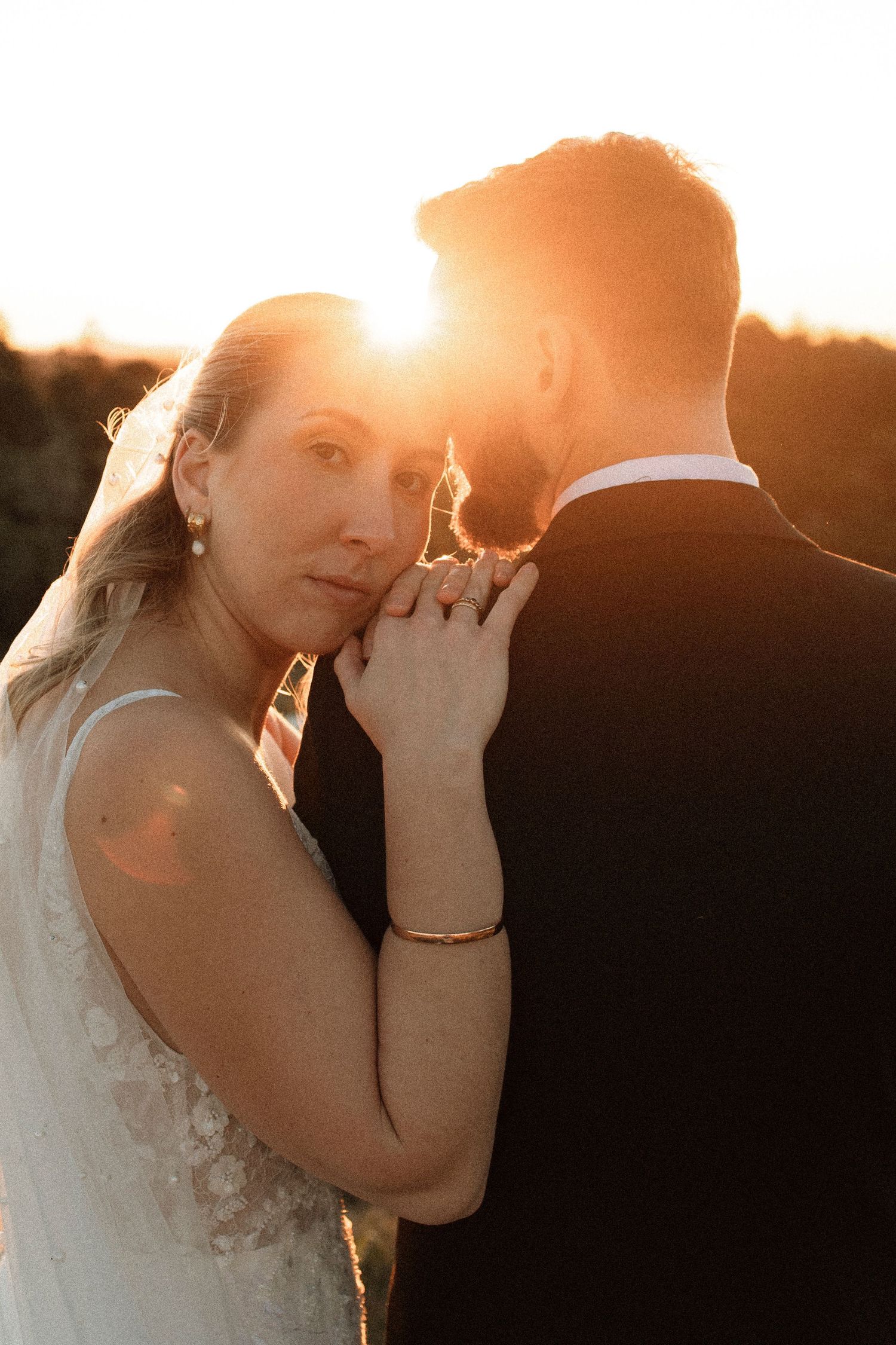 Romantic sunset silhouette of couple in wedding attire sharing an intimate moment with golden light glowing behind them. The Firebreak