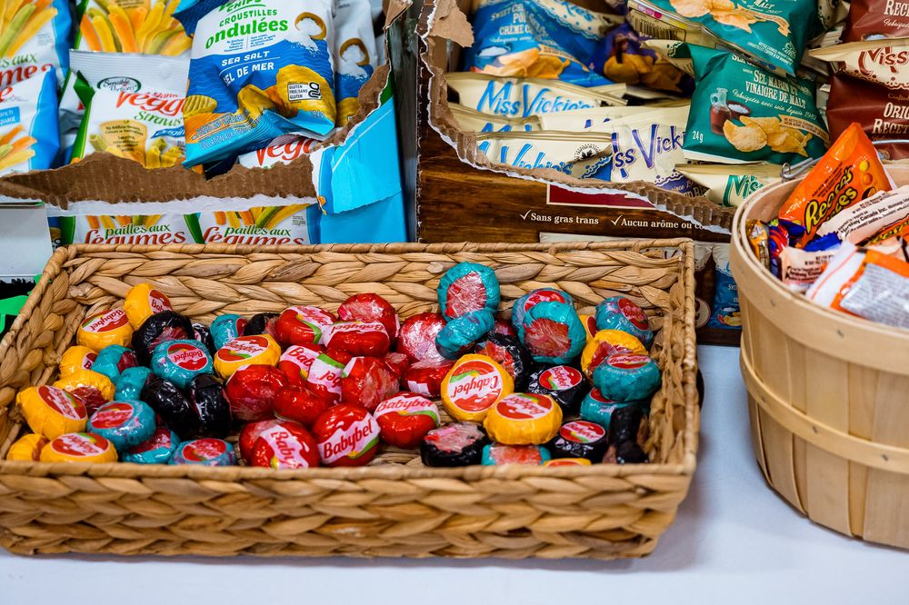 Woven baskets filled with colorful wrapped chocolates and candies displayed on wooden surface.