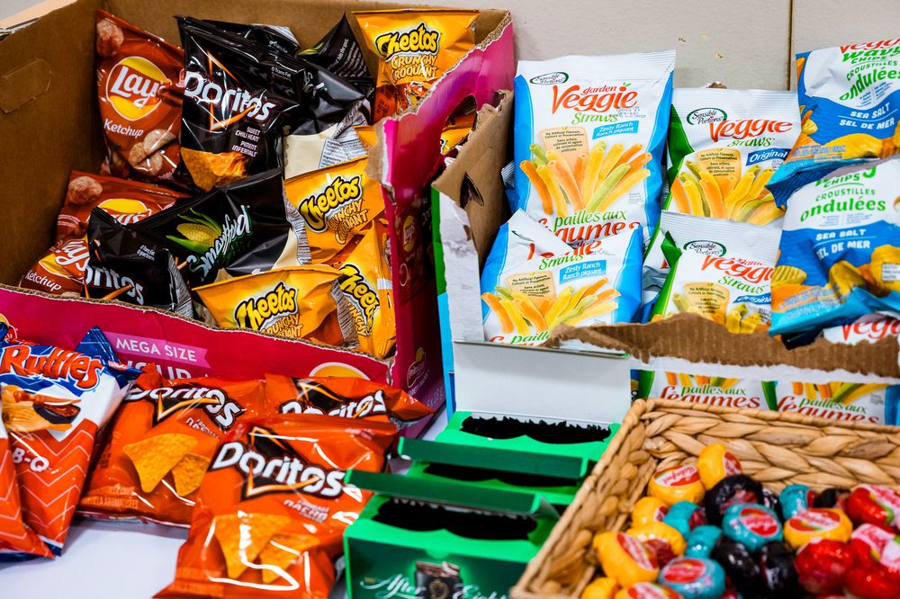Colorful assortment of snack food bags and chip packages displayed in rows on a surface.