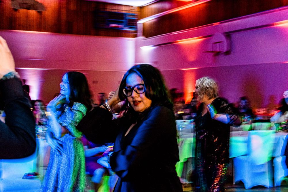 People dancing at a nightclub with colorful blue and pink lighting creating a vibrant party atmosphere.