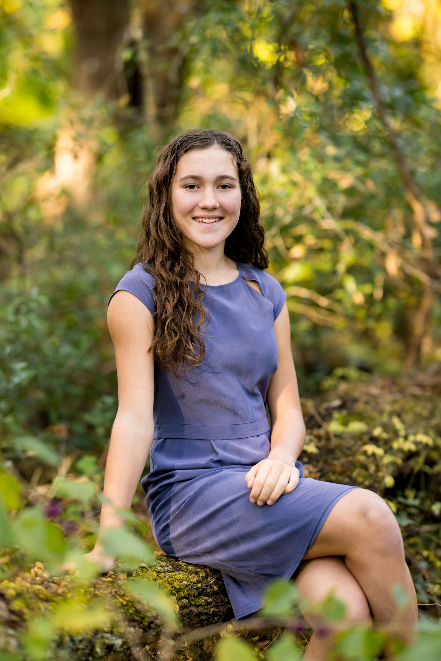 A series of outdoor portrait shots in a purple dress sitting among autumn foliage with natural lighting.