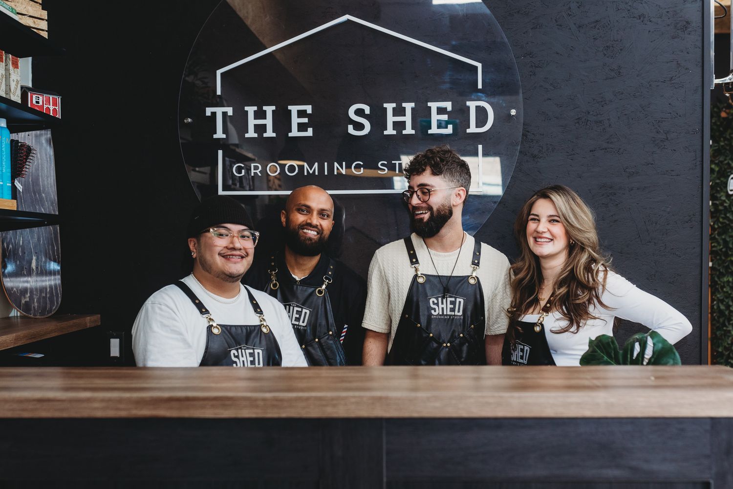 Staff members wearing black aprons stand together behind the counter at The Shed Grooming Co.