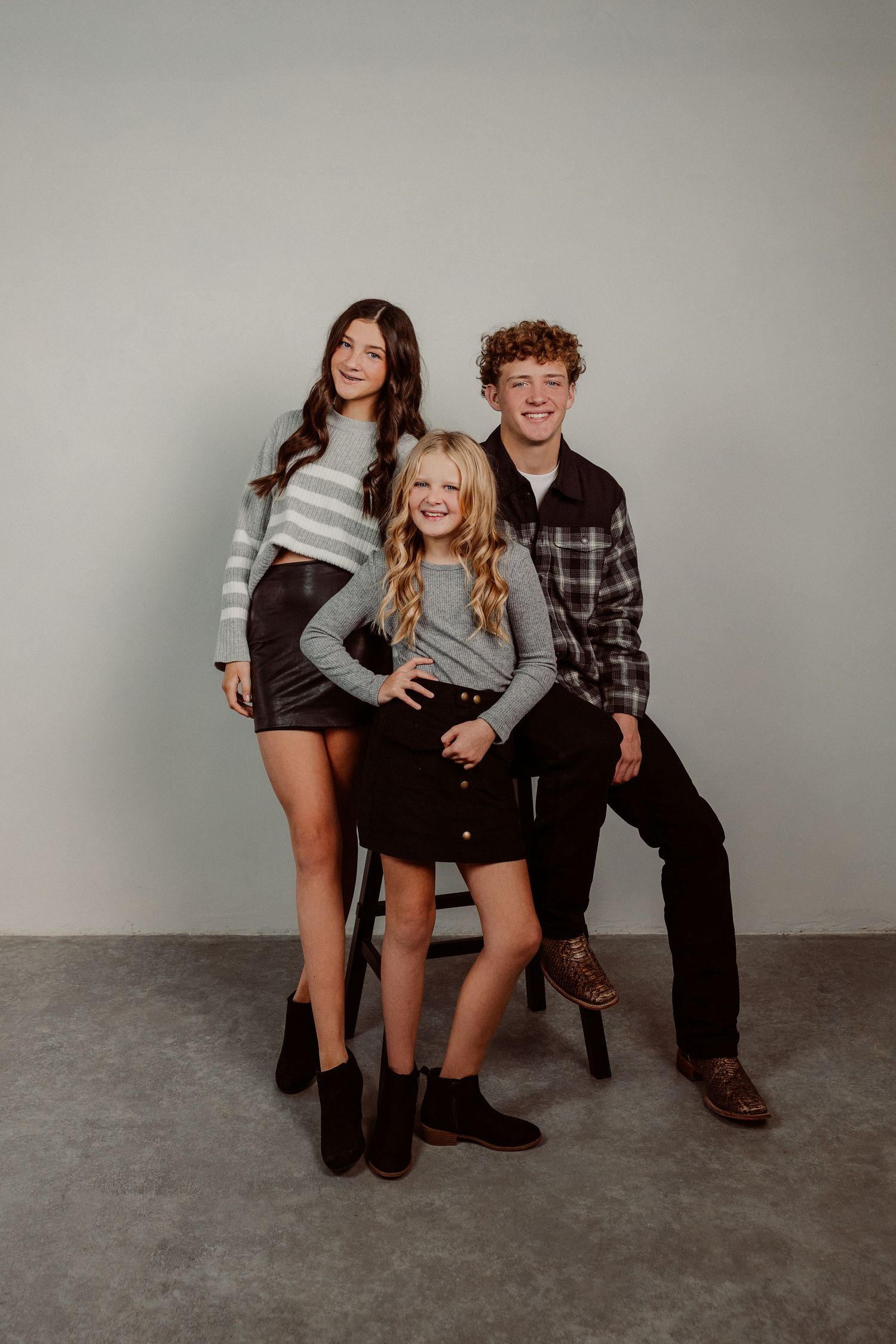 Casual lifestyle photoshoot with people sitting and laughing together on a grey backdrop.