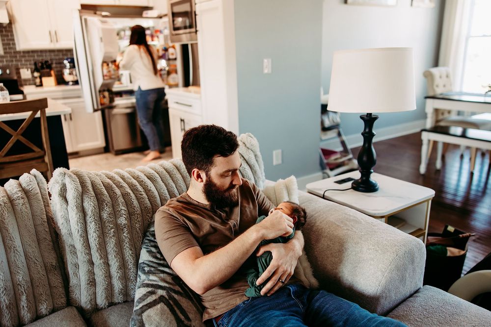 Person relaxing on gray couch in modern living room while using smartphone in natural lighting.
