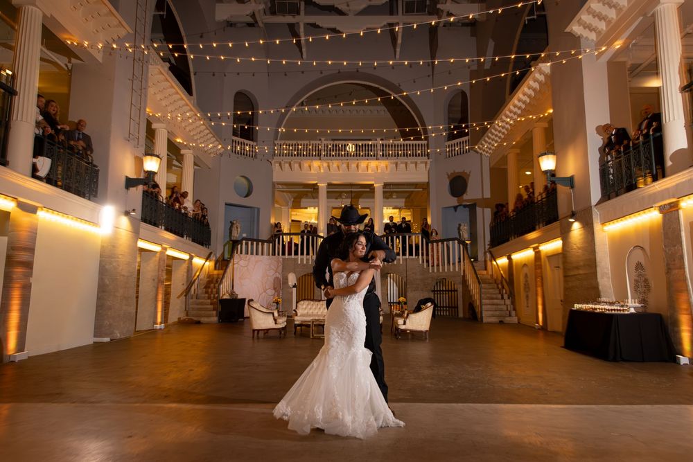 Elegant wedding reception venue with string lights and white decor creating a romantic ambiance in a historic building.