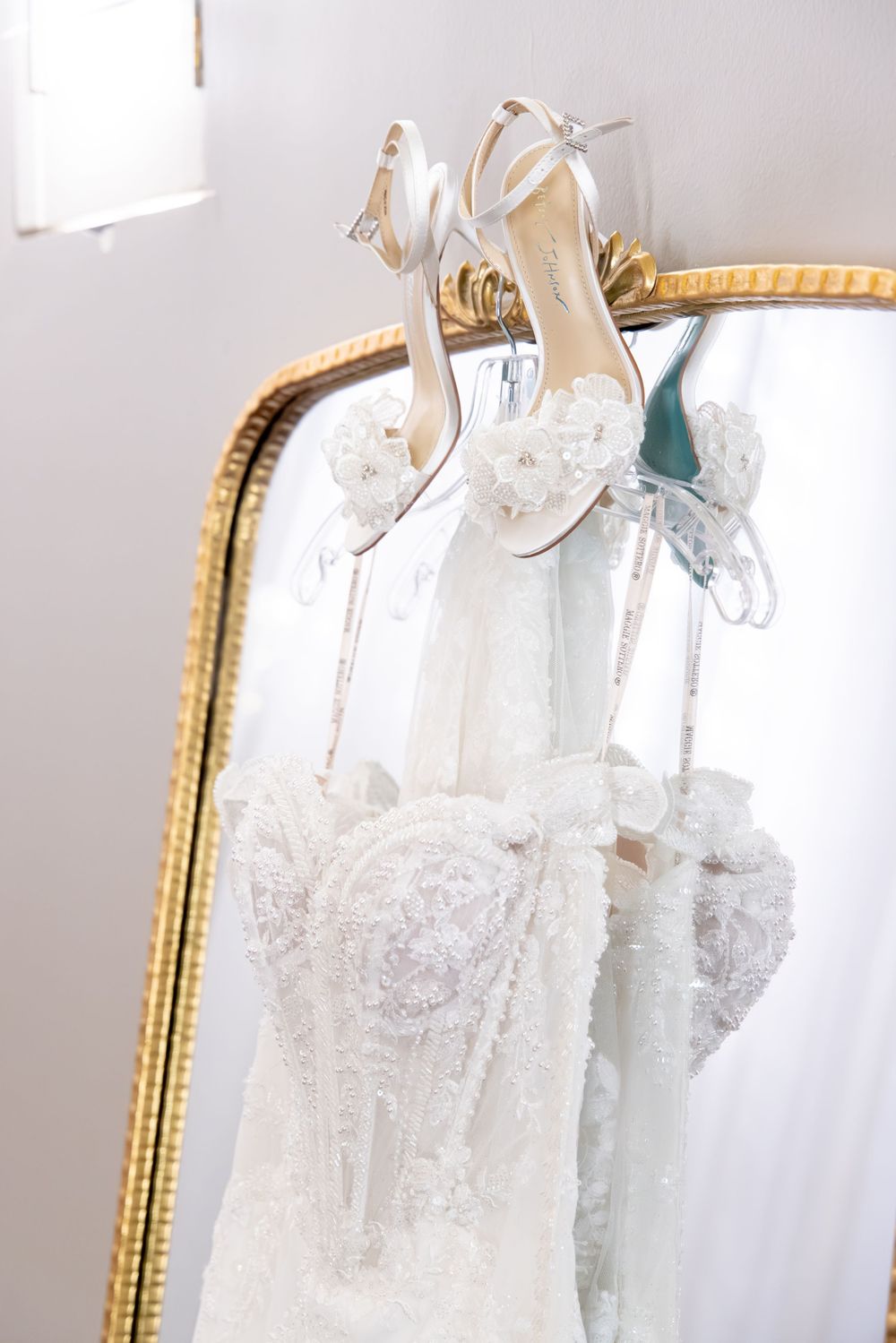 White wedding dresses hanging on display with intricate lace and beaded details against a light background.