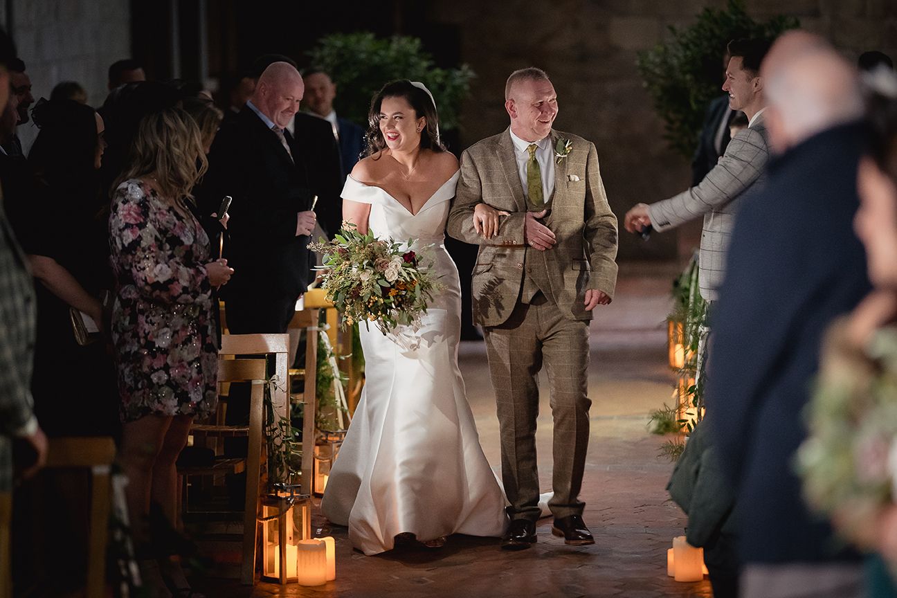 Evening wedding celebration with guests and couple dancing in candlelit outdoor setting.