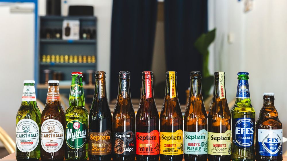 A long row of assorted beer bottles lined up on a shelf showing different international and craft beer brands.