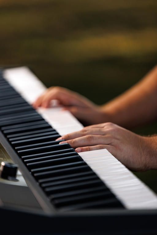 Close-up sequence of hands playing an electronic keyboard piano in warm sunlight.