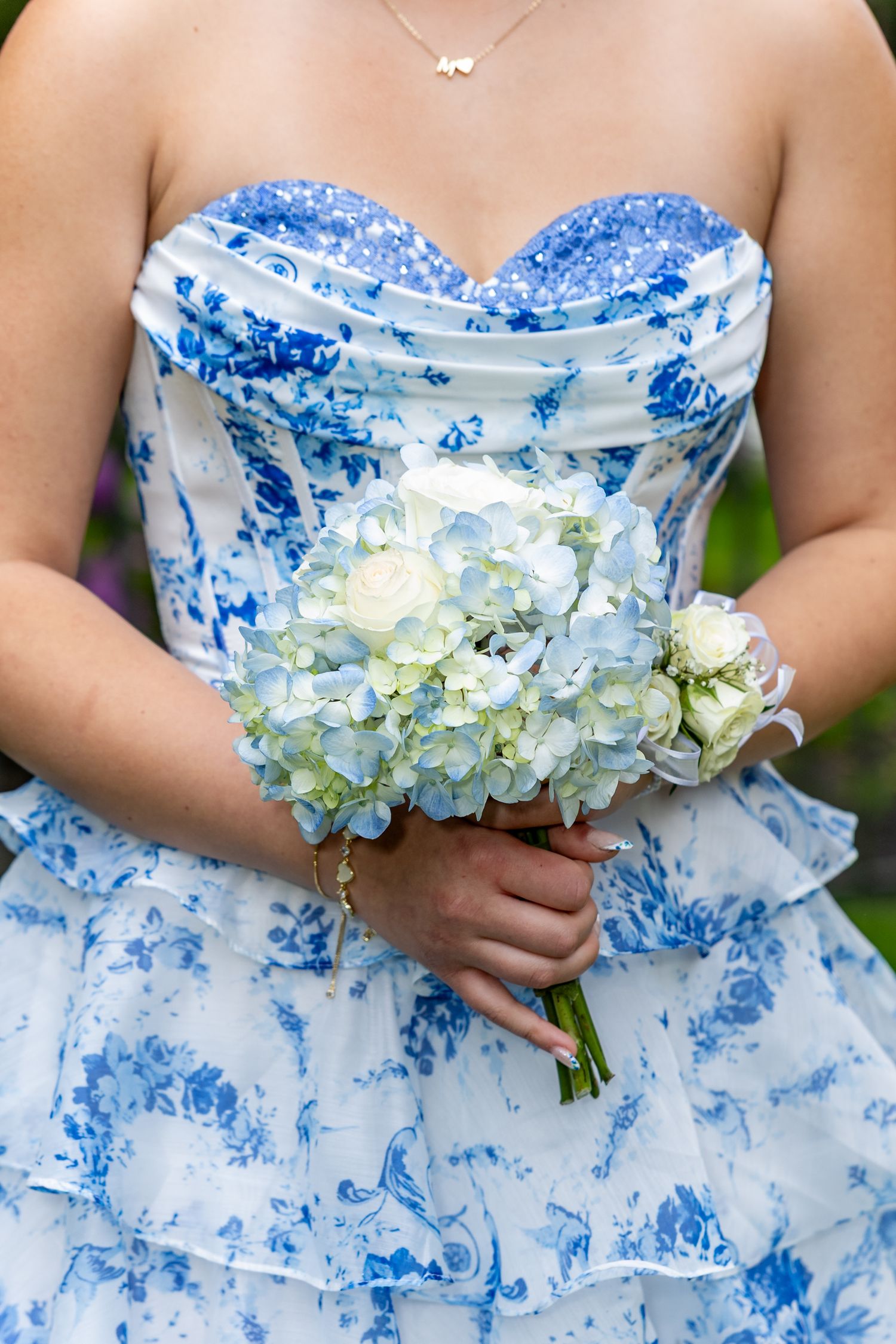 A strapless blue and white floral dress with a sweetheart neckline paired with a delicate hydrangea bouquet at pre prom group photo shoot.