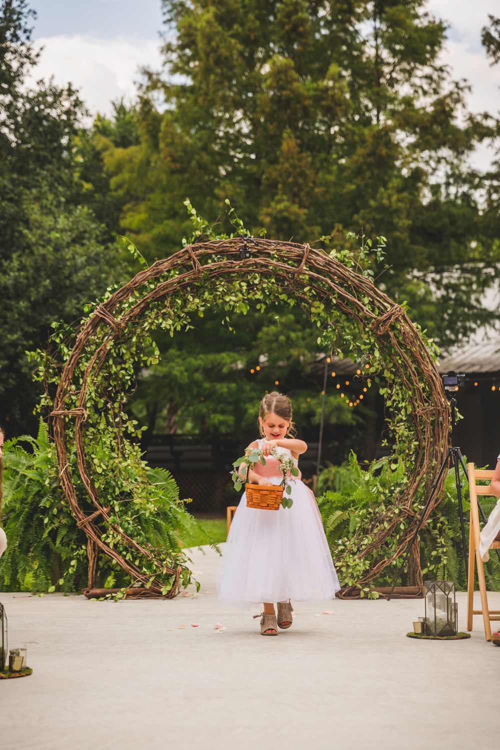 A rustic garden archway decorated with twinkle lights creates a romantic wedding pathway.