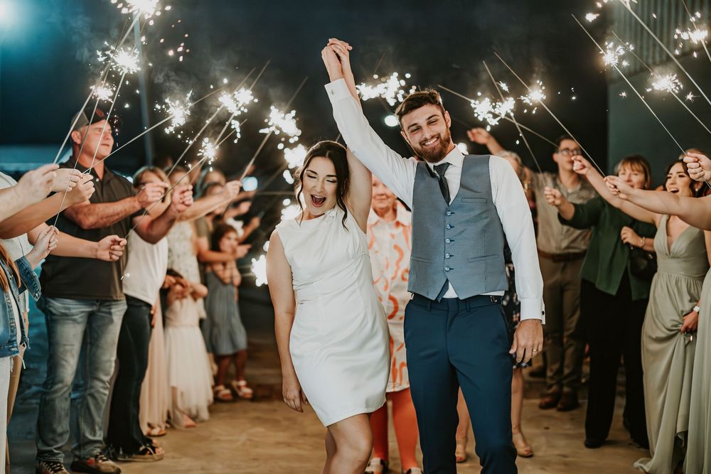 Sparklers illuminate a joyful wedding celebration under the night sky.