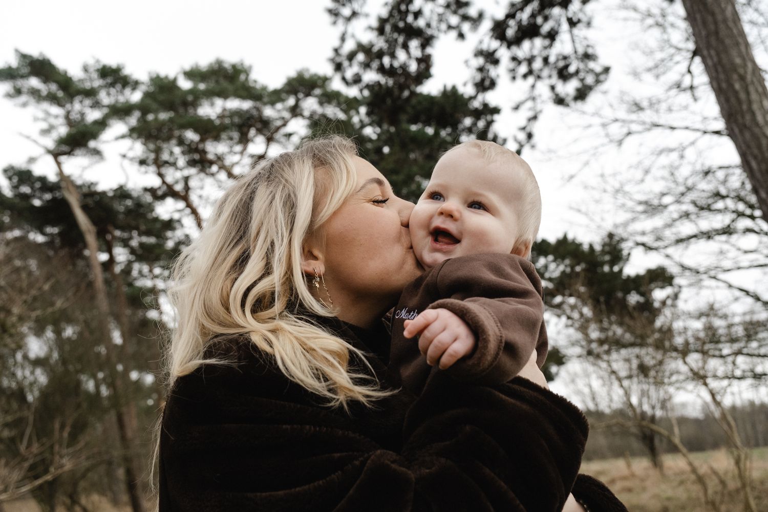 Sweet tender moment between parent and baby against white backdrop with soft natural lighting.