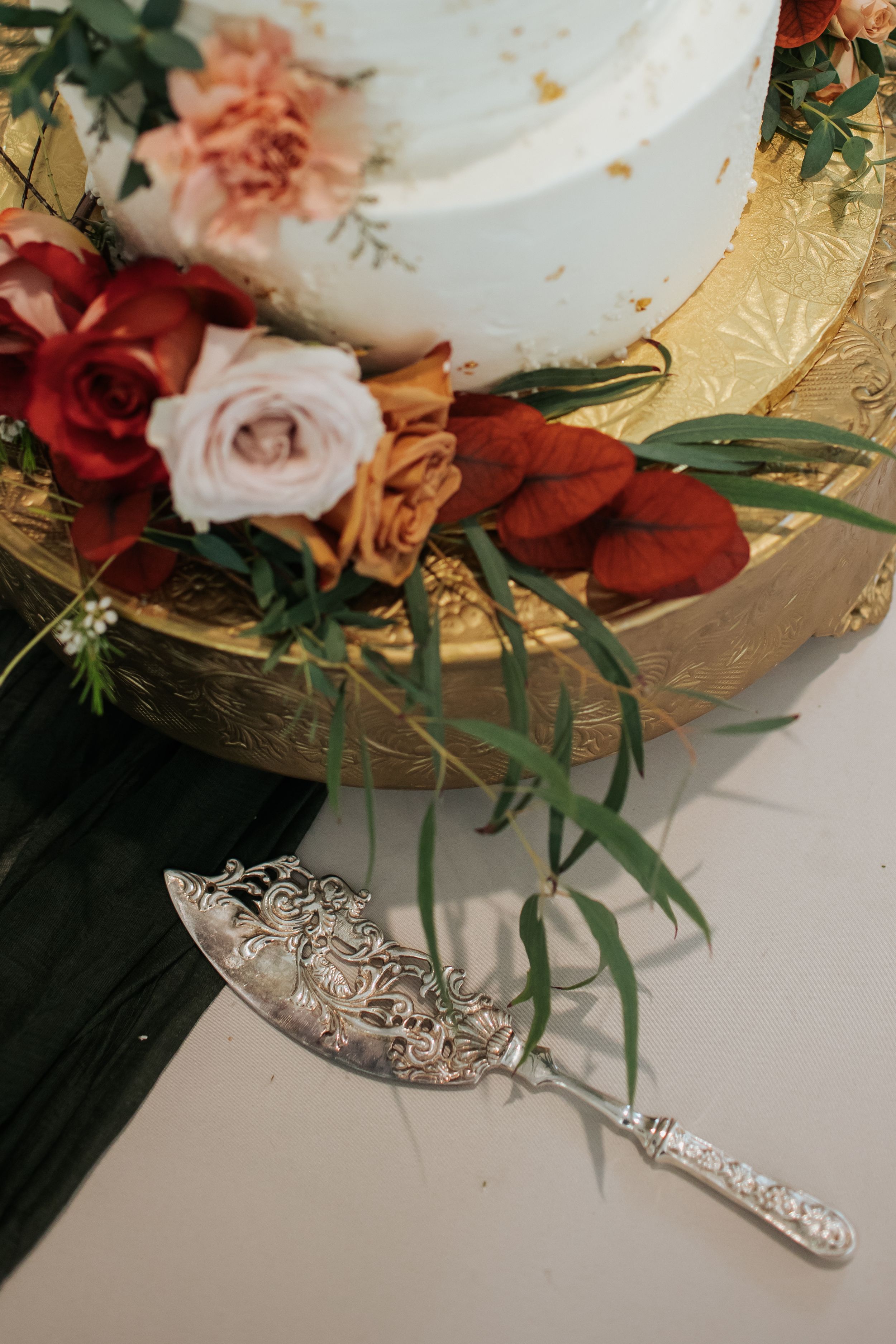 Elegant wedding decor featuring ornate silver tiaras displayed alongside coral and white roses on a textured surface.