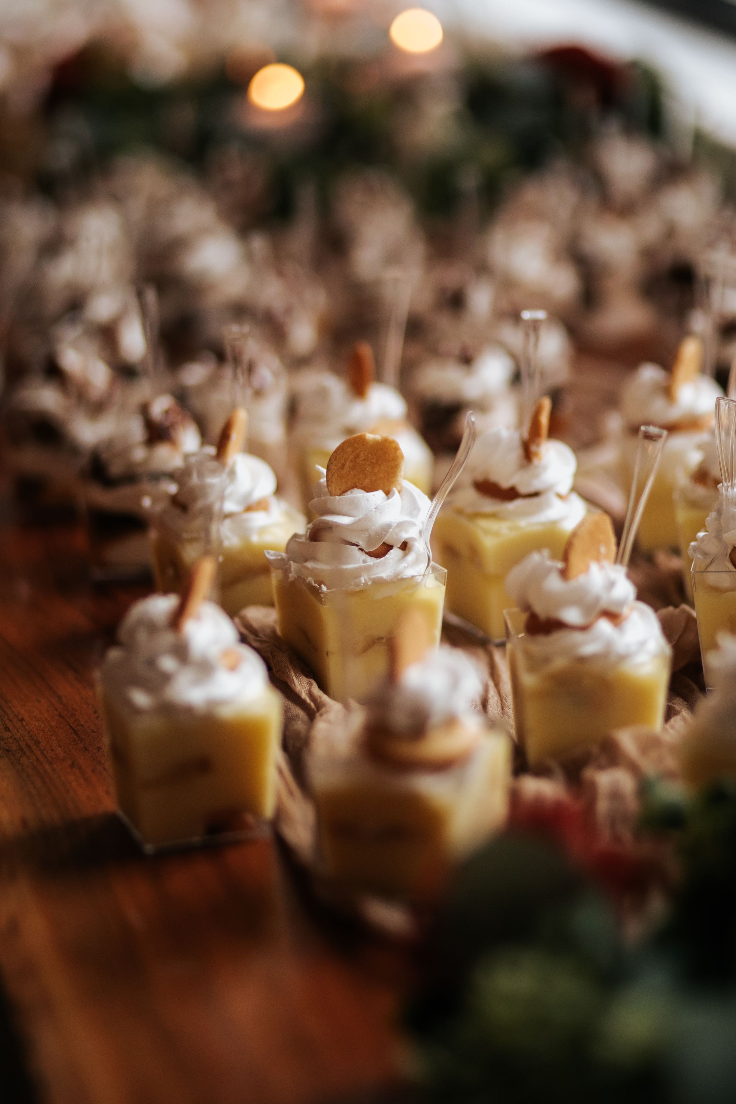 Individual servings of banana pudding topped with whipped cream and garnished with vanilla wafers in small glass cups.