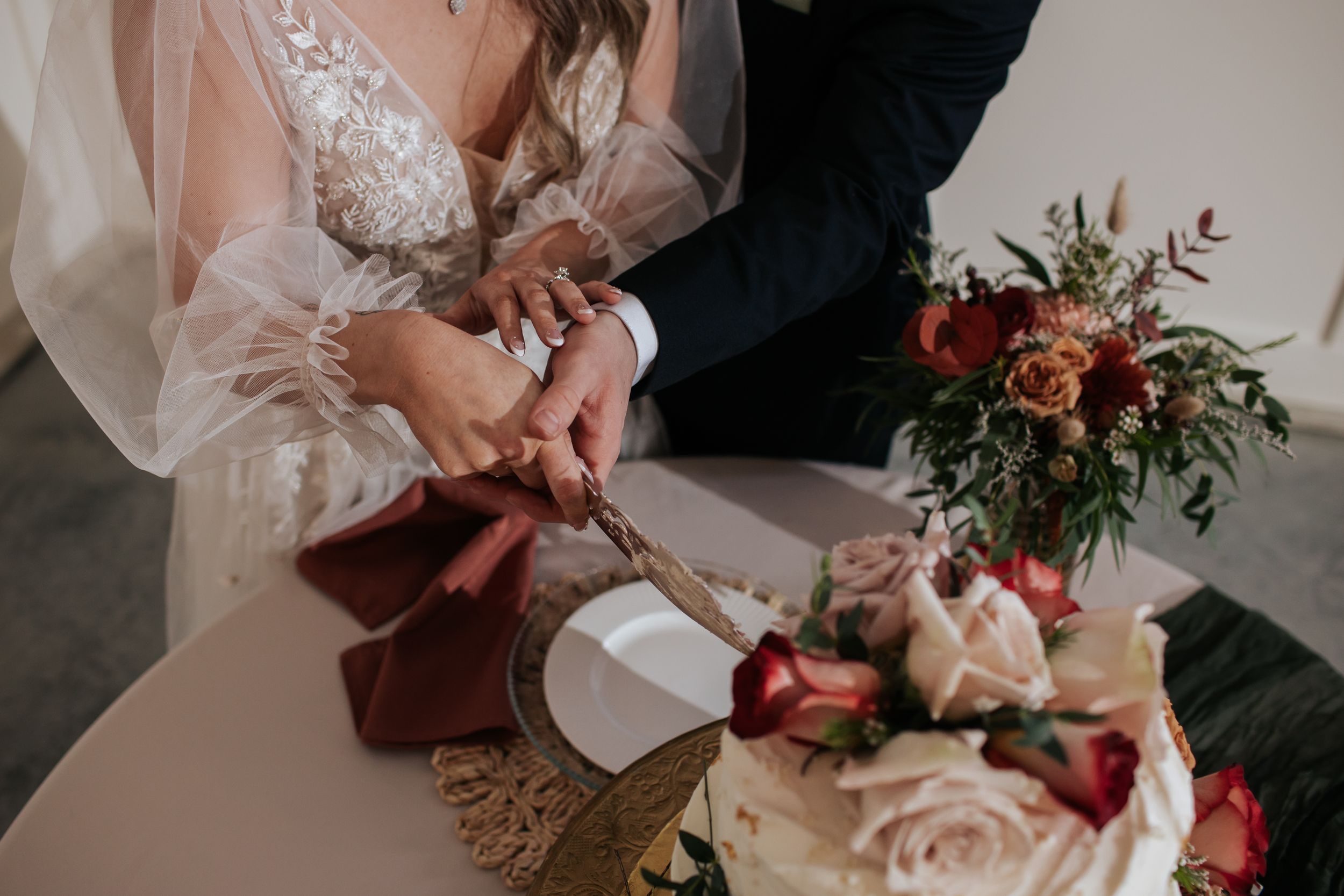 Elegant wedding bouquet features blush roses and deep burgundy florals with cascading greenery.