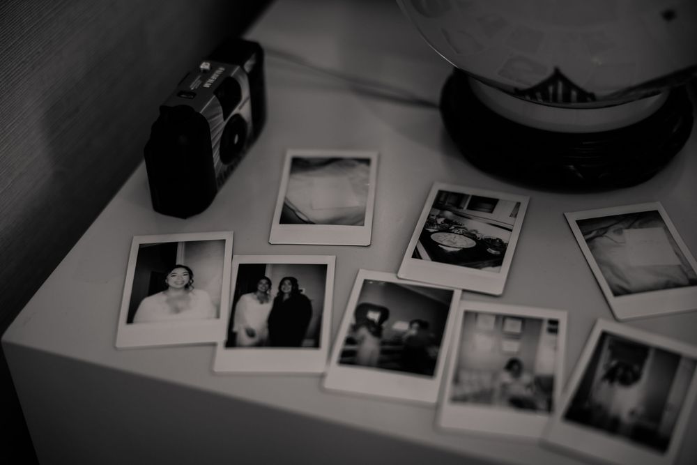 Vintage polaroid photos and camera arranged on a white surface in black and white.
