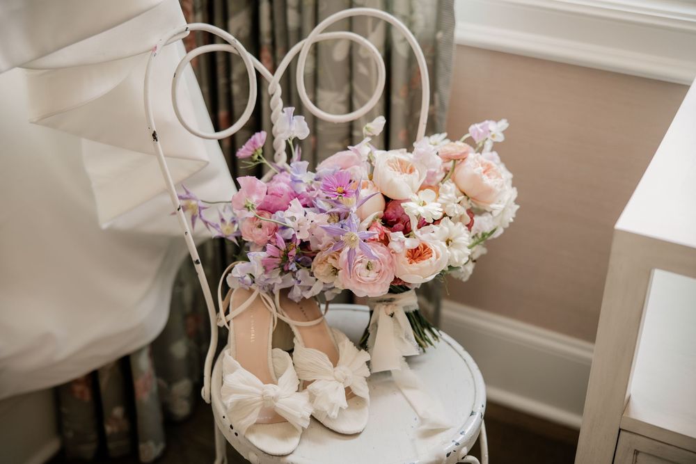 Wedding accessories including pink floral arrangements and bridal shoes.