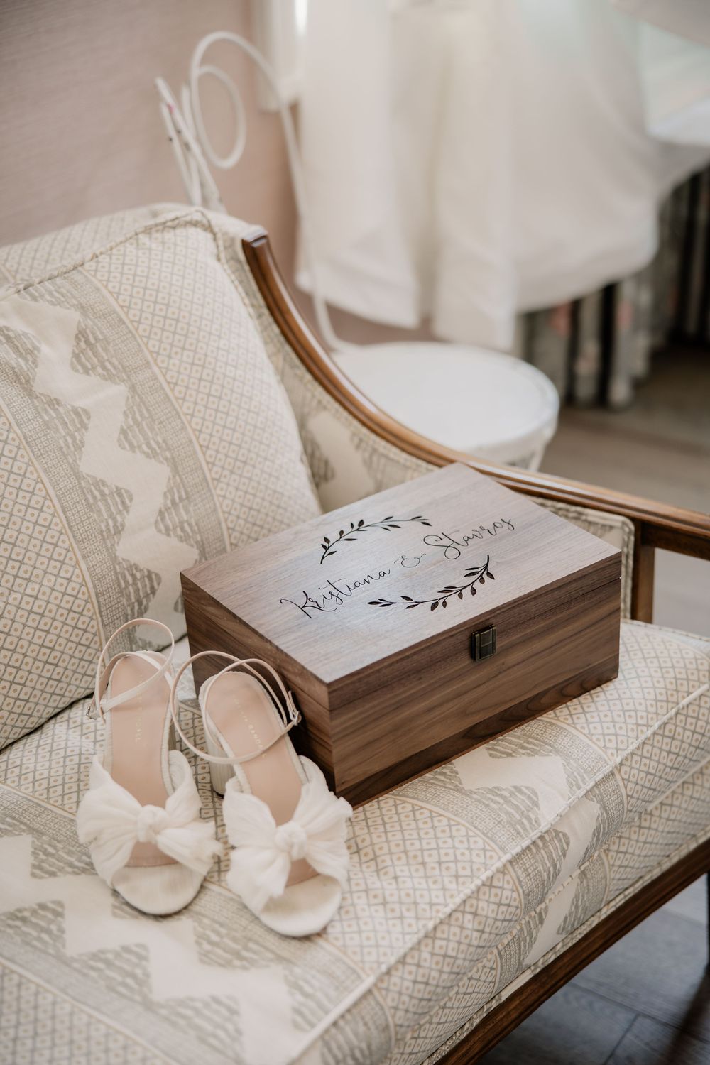 Wedding accessories including shoes and a wooden box arranged on a textured white surface.