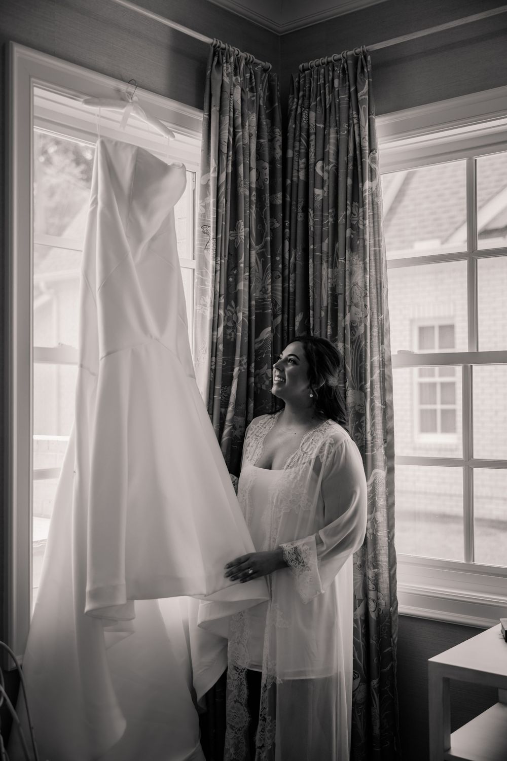 Black and white series showing wedding dress preparations with flowing white gowns hanging by windows.