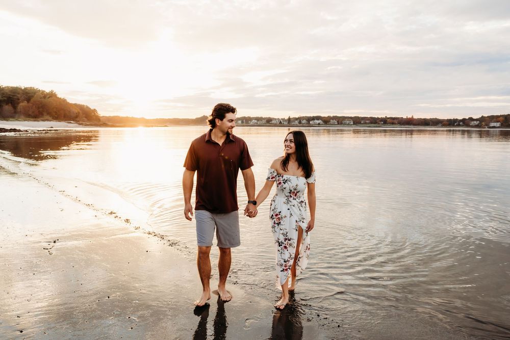 Romantic couple walking together along a serene beach at sunset, holding hands and enjoying the ocean view.