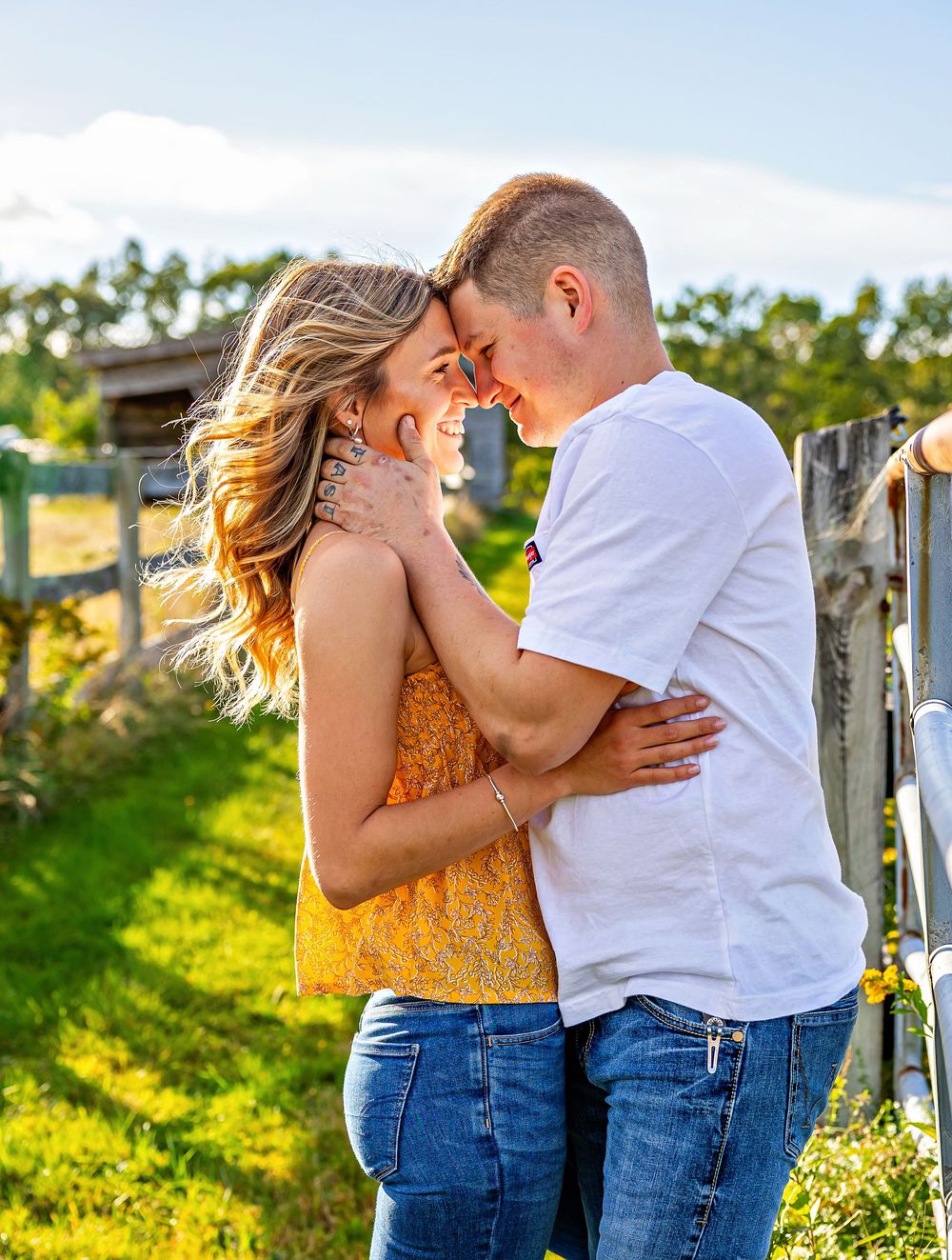 Couple in matching denim and white outfits embracing in a sunlit field with golden wildflowers.
