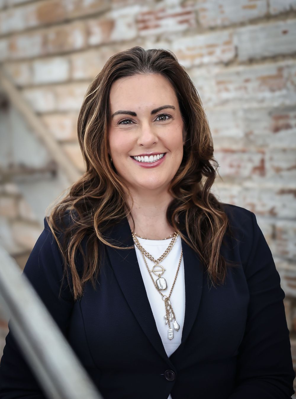 Professional portrait against rustic brick wall background.