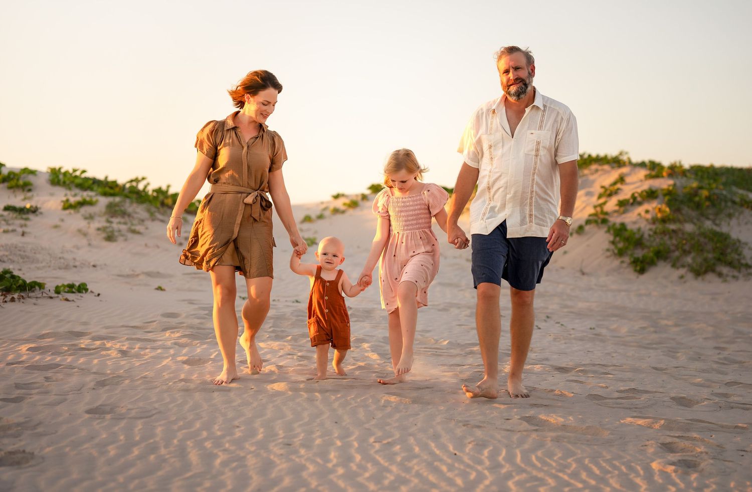 Family walking together along sandy dunes at sunset in Matagorda Beach, Texas during a relaxed beach photo session