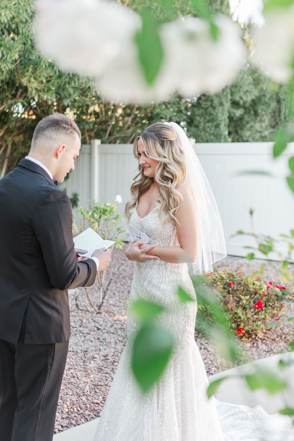 Bride and groom share an intimate first look moment in a garden with white flowers.