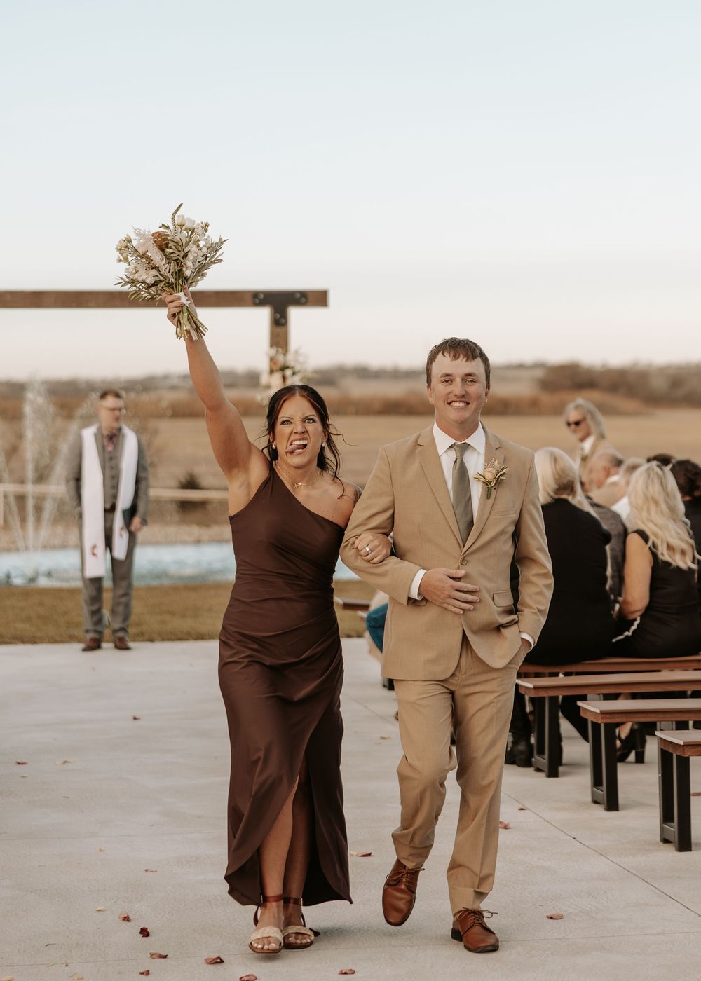 Wedding party celebrates joyfully while walking together outdoors at sunset.