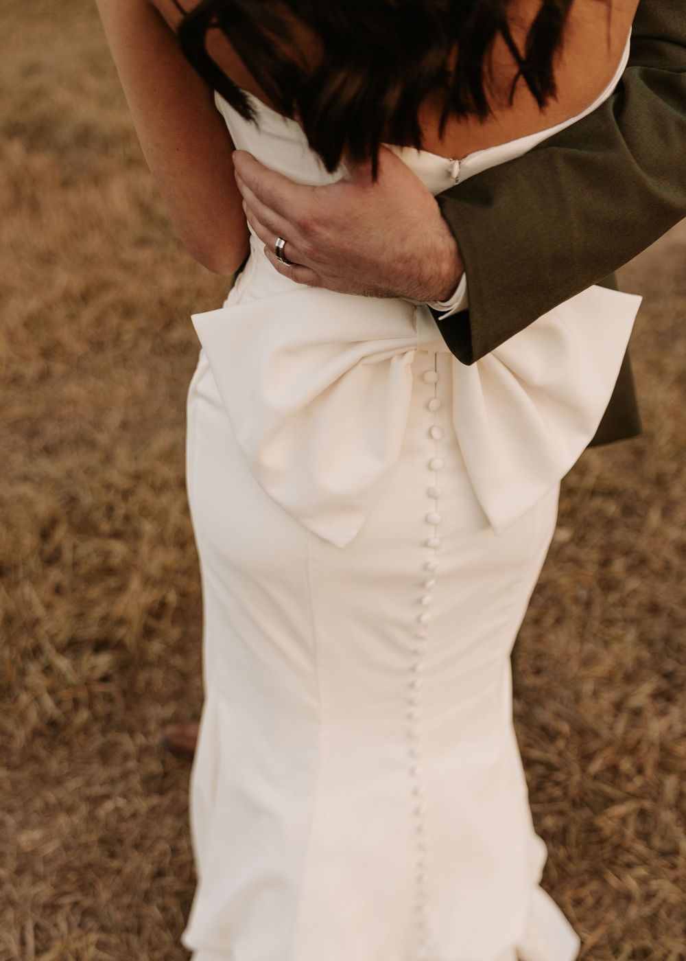 Close-up details of a white wedding dress with button details down the back.