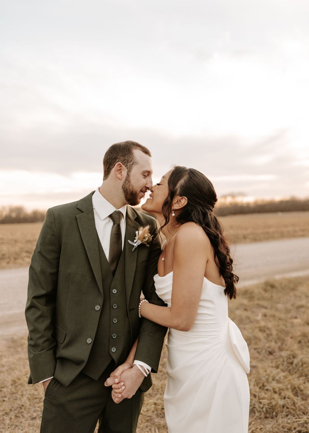 Romantic wedding couple shares intimate moments in a golden field during sunset.
