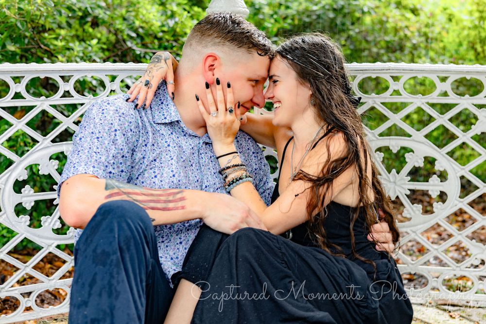 Couple shares intimate kisses along a white lattice fence in a romantic garden setting.