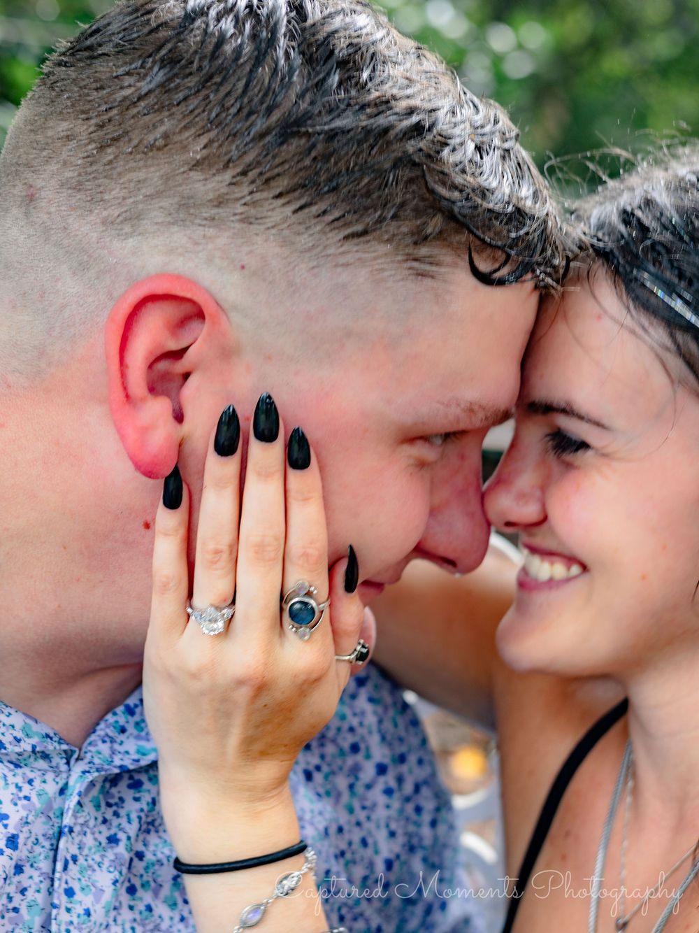 A couple shares an intimate moment wearing matching floral prints against a soft blurred background.