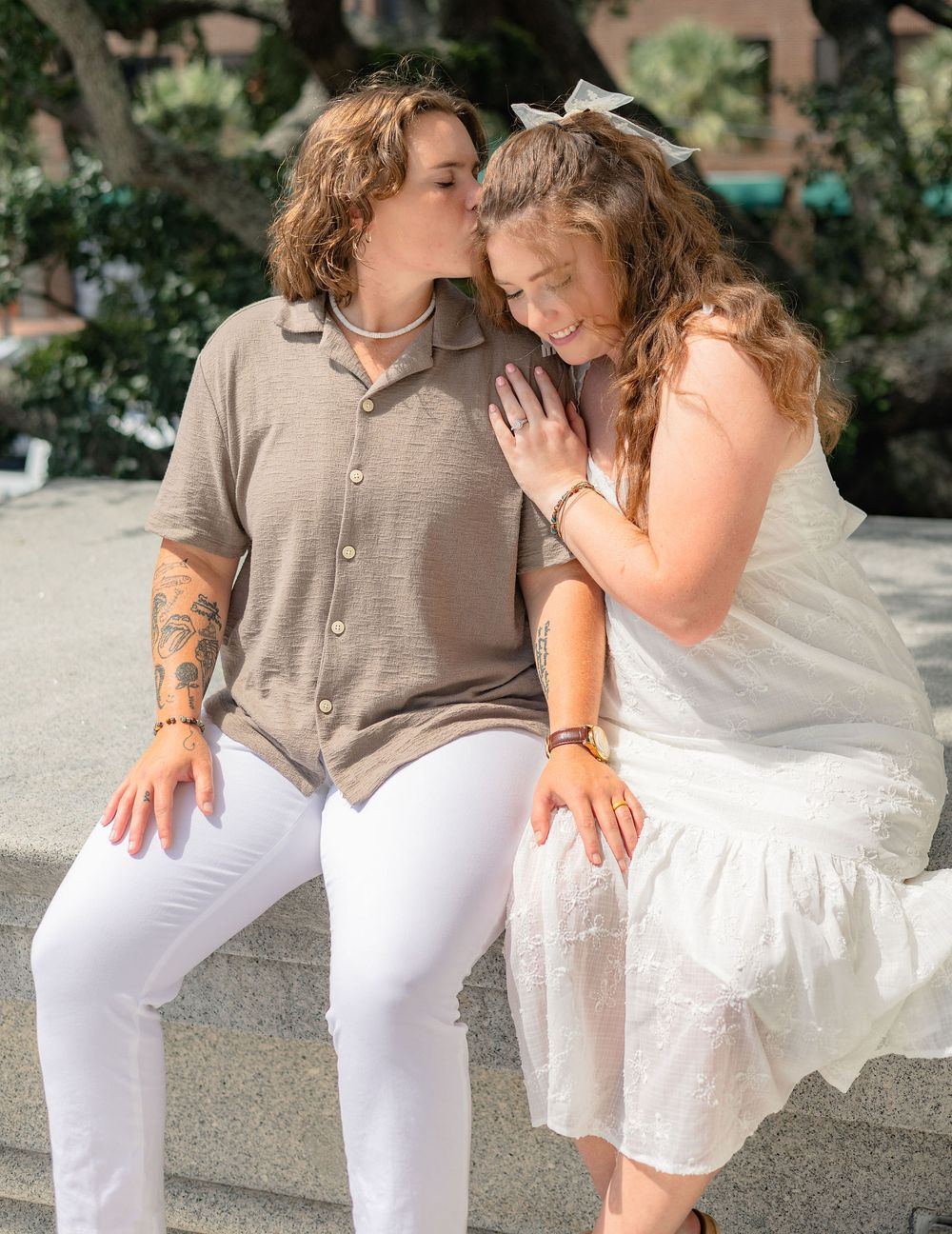 A couple in casual attire sharing intimate moments while sitting on outdoor steps.