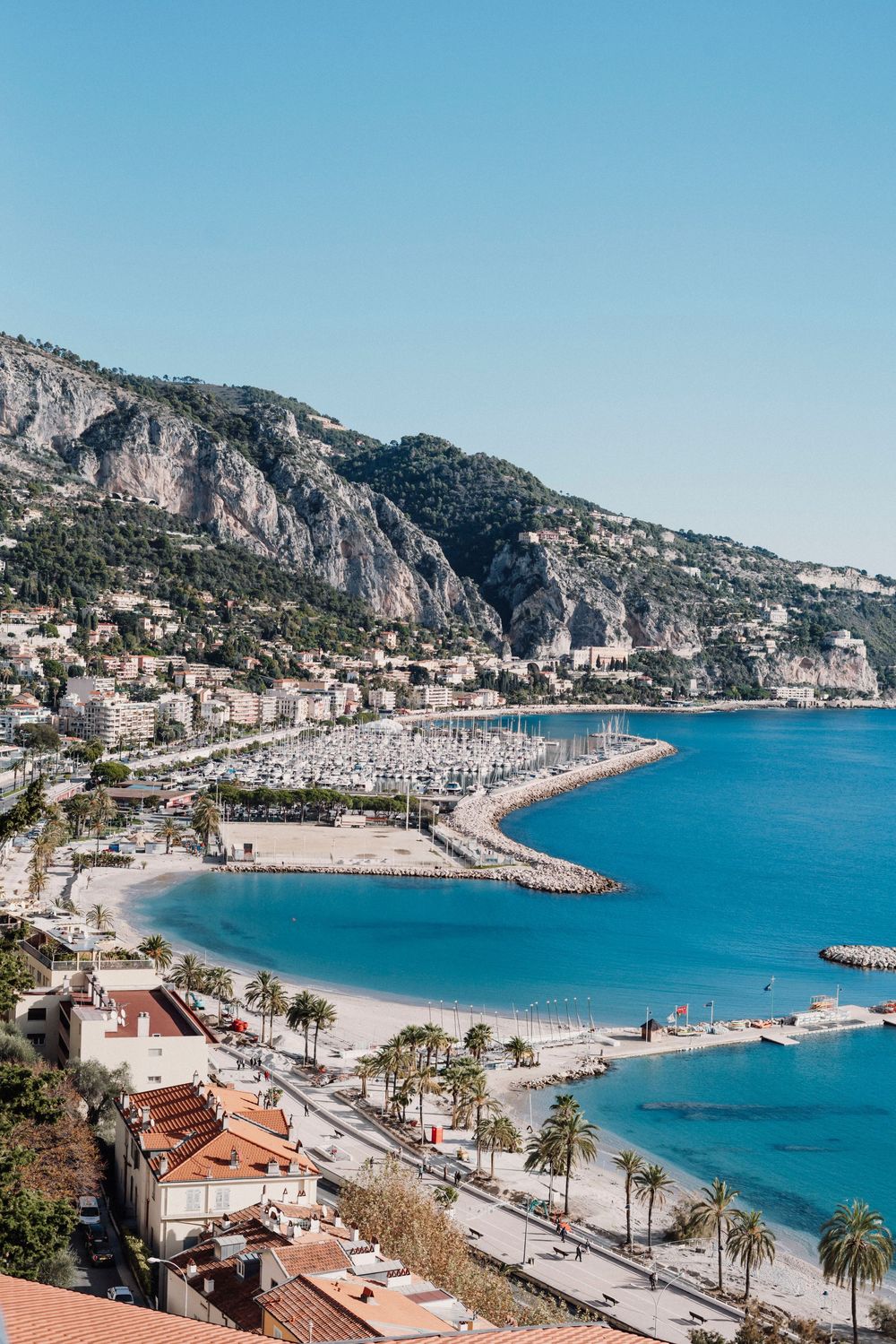 Panoramic view of Menton beach and coastline with turquoise Mediterranean waters and mountains in the French Riviera.