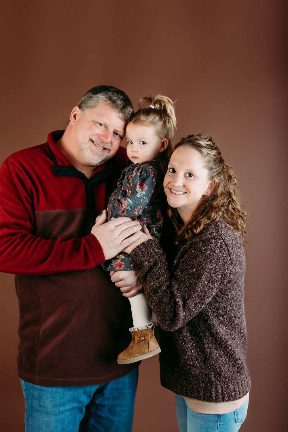 A series of four intimate family portraits showing tender moments between parent and child against a brown backdrop.